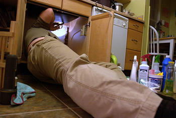 Plumber checking pipes under sink